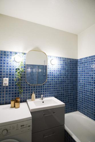une salle de bain carrelée bleue avec un lavabo et une baignoire dans l'établissement -SUNSET- Front de mer avec terrasse et parking, à Concarneau