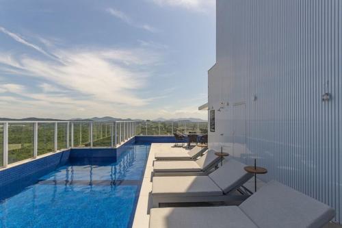 a swimming pool with chairs and tables on a building at Apto 3Q c/ piscina e acad. 180m - LTT803 in Piçarras