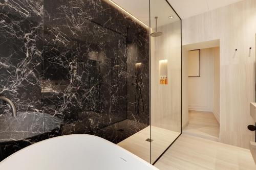 La salle de bains est pourvue d'une douche et d'un mur en marbre noir. dans l'établissement TheLander - Serviced Apartment in Le Marais, à Paris
