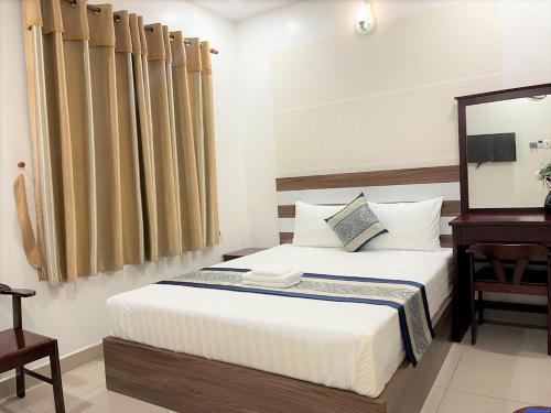um quarto com uma cama com uma mesa e um espelho em DINH DINH 2 AIRPORT HOTEL em Cidade de Ho Chi Minh