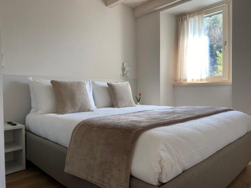 a bedroom with a large white bed with a window at Ca Marièt casa vacanze in Chiavenna