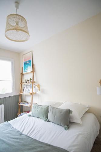 une chambre avec un lit avec des draps blancs et des oreillers dans l'établissement -UGO- T1 bis avec parking proche plage, à Concarneau