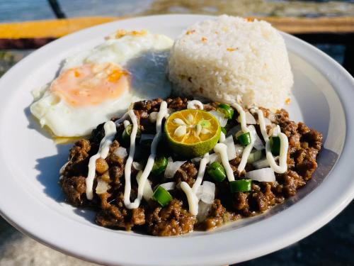 a plate of food with a fried egg and rice at La Concepcion Cove Garden Resort in Moalboal