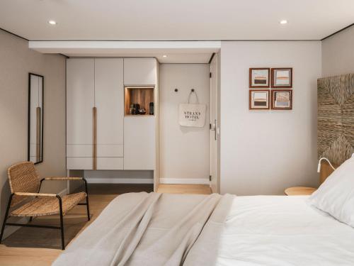 a bedroom with a bed and a chair at Strandhotel Domburg - Next Door in Domburg
