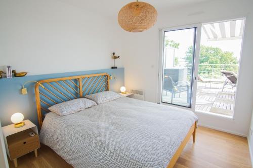 une chambre avec un lit avec une tête de lit bleue et un balcon dans l'établissement -La Terrasse- T2 avec Terrasse vue mer, à Concarneau