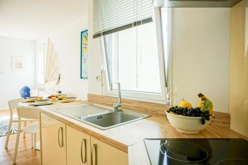 - une cuisine avec un évier et un bol de fruits sur le comptoir dans l'établissement -La Terrasse- T2 avec Terrasse vue mer, à Concarneau