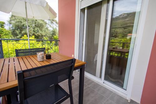 a wooden table and chairs on a balcony with a window at Aurora Premium Hospitality in Parga