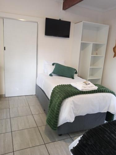 a bedroom with a bed with a green blanket on it at Cozy Corner in Groblersdal