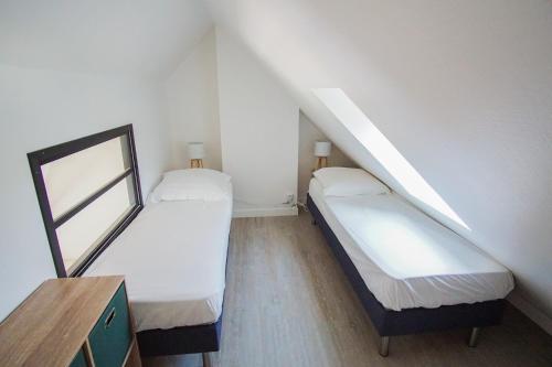 Cette petite chambre mansardée comprend 2 lits. dans l'établissement -Octant-Magnifique T1bis a Port La Foret Fouesnant, à La Forêt-Fouesnant