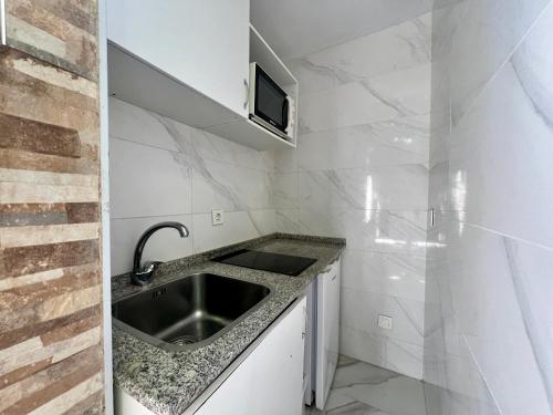una pequeña cocina con fregadero y TV en Boutique Princesa, en Marbella
