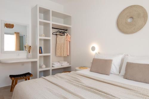 a white bedroom with a bed and a mirror at Porte Accommodation in Kamarai
