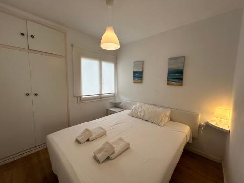 a white bedroom with a bed with two towels on it at Sa Posta in Cala en Forcat