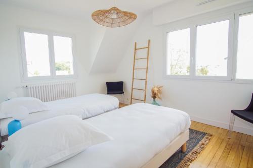 two beds in a room with white walls and windows at -ERNEST-Maison avec jardin a 200m des plages in Concarneau