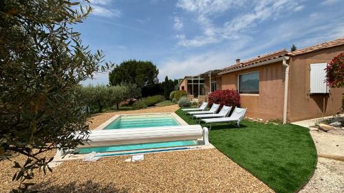 une cour arrière avec une piscine avec deux chaises blanches et une maison dans l'établissement La Villa Tanamera, très jolie maison piscine, à 2 pas du centre-ville, à Bédoin