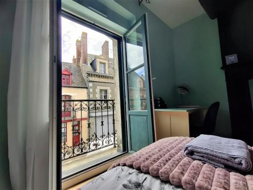 a bedroom with a window with a view of a building at Appartement EMILiA Centre ville in Vitré
