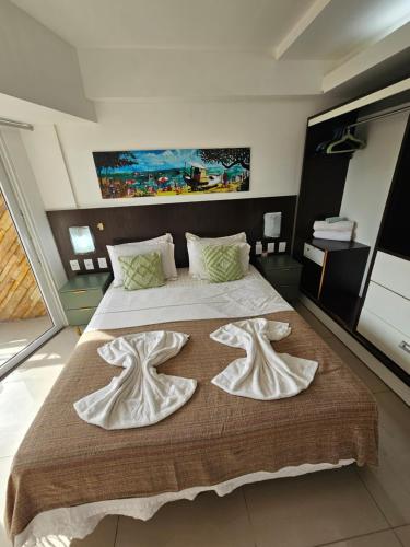 a bedroom with a large bed with two white towels at Flat with sea view Pipa's Bay in Pipa