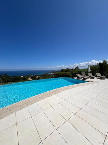 une piscine avec des chaises et l'océan en arrière-plan dans l'établissement Villa Vue Mer Exceptionnelle 5 Chambres, à Sainte-Maxime