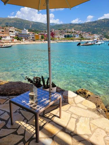 a table with an umbrella next to the water at Artis Blue Relax in Himare