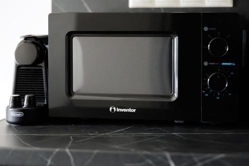 a black microwave oven sitting on top of a counter at Ilios Properties - next to Gouvia Beach in Gouvia