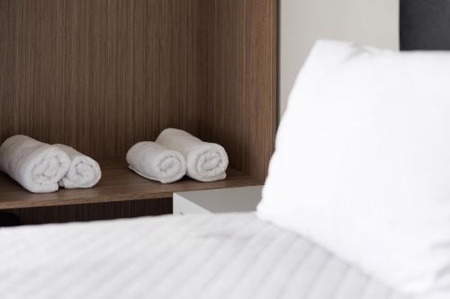 three rolled towels on a shelf next to a bed at Ilios Properties - next to Gouvia Beach in Gouvia