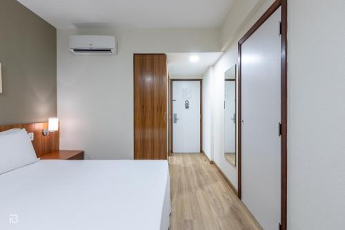 烏貝蘭迪亞的住宿－行政酒店，卧室配有一张白色大床和镜子