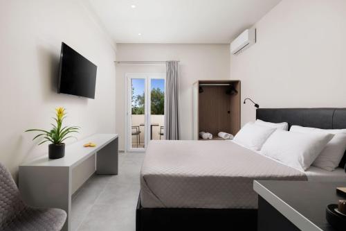 a bedroom with a bed and a tv and a chair at Ilios Properties - next to Gouvia Beach in Gouvia