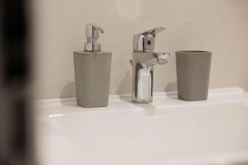 a bathroom sink with a faucet and two cups at Ilios Properties - next to Gouvia Beach in Gouvia
