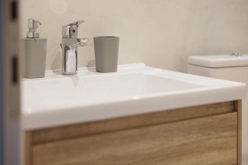 a bathroom sink with two cups on top of it at Ilios Properties - next to Gouvia Beach in Gouvia