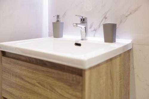 a bathroom sink with two cups on top of it at Ilios Properties - next to Gouvia Beach in Gouvia