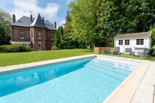 a swimming pool in front of a house at Le Manoir de la belle epoque in Béthencourt-sur-Mer
