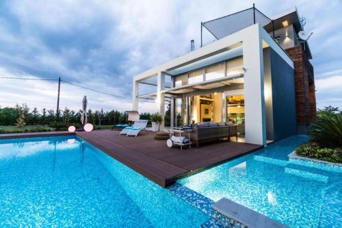a house with a swimming pool in front of a house at Island Villa Sani Sea View in Sani Beach