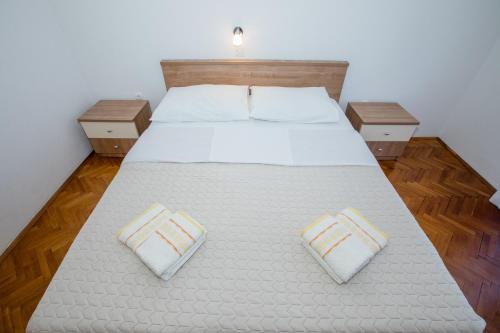 a bedroom with a large white bed with two pillows at Apartmani Zdenka in Rab
