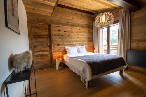 une chambre avec un lit dans une pièce aux murs en bois dans l'établissement Smartstay La Nuit Etoilee - Megeve, à Demi-Quartier