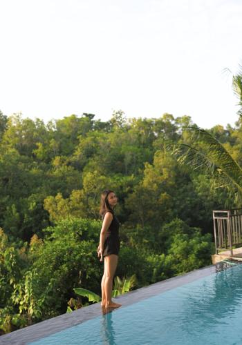 a woman standing on the edge of a swimming pool at Innala Retreat Nusa Penida in Nusa Penida