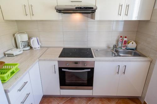 a kitchen with a sink and a stove at Apartmani Zdenka in Rab