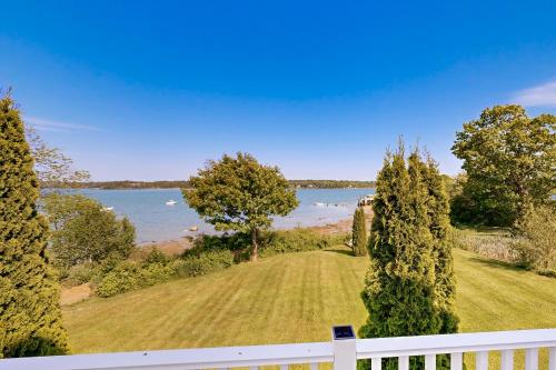 a house with a white fence and a view of the water at Clark Cove in Harpswell Center
