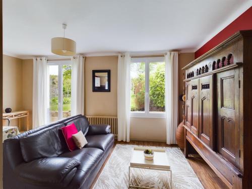 a living room with a leather couch and windows at -HARES- Maison authentique avec jardin in Trégunc