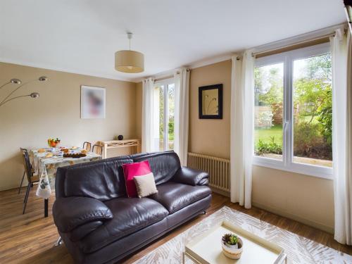 a living room with a leather couch and a table at -HARES- Maison authentique avec jardin in Trégunc