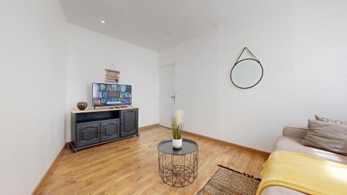 a living room with a couch and a tv at Cosy et Chic Centre Ville in Tulle