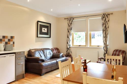 a living room with a leather couch and a table at Lodges by Atholl Palace in Pitlochry