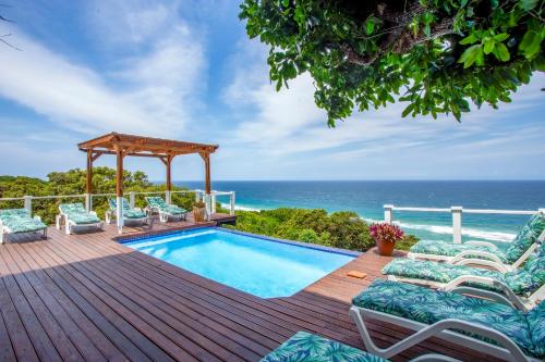 a swimming pool on a deck with chairs and the ocean at Naudicals Dune in Chefe Imala