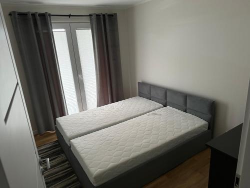 a bedroom with a bed in a room with a window at Apartament Centrum Łeba in Łeba
