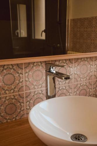 a bathroom sink with a faucet on a tiled wall at -LES LUTINS- Charmante maison les pieds dans l eau in Concarneau