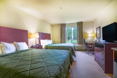 a hotel room with two beds and a flat screen tv at Evansville Inn & Suites by OYO in Evansville