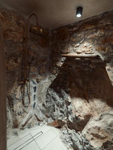 a bathroom with a shower in a stone wall at KaSeas Boutique Hotel in Gerolimenas