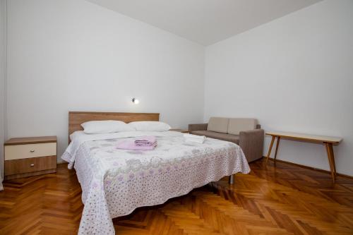 a bedroom with a bed with a table and a chair at Apartmani Zdenka in Rab