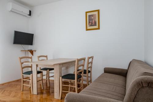a living room with a couch and a table and chairs at Apartmani Zdenka in Rab