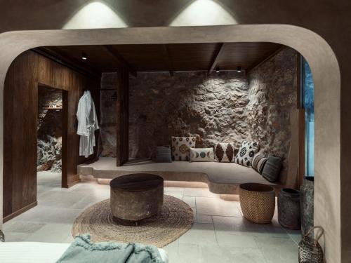 a room with a stone wall with a bed with chairs at KaSeas Boutique Hotel in Gerolimenas