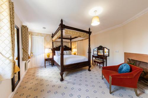 a bedroom with a canopy bed and a red chair at Lodges by Atholl Palace in Pitlochry