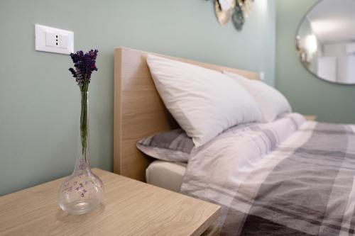 a vase with purple flowers sitting on a table next to a bed at Le Lavande in Castro
